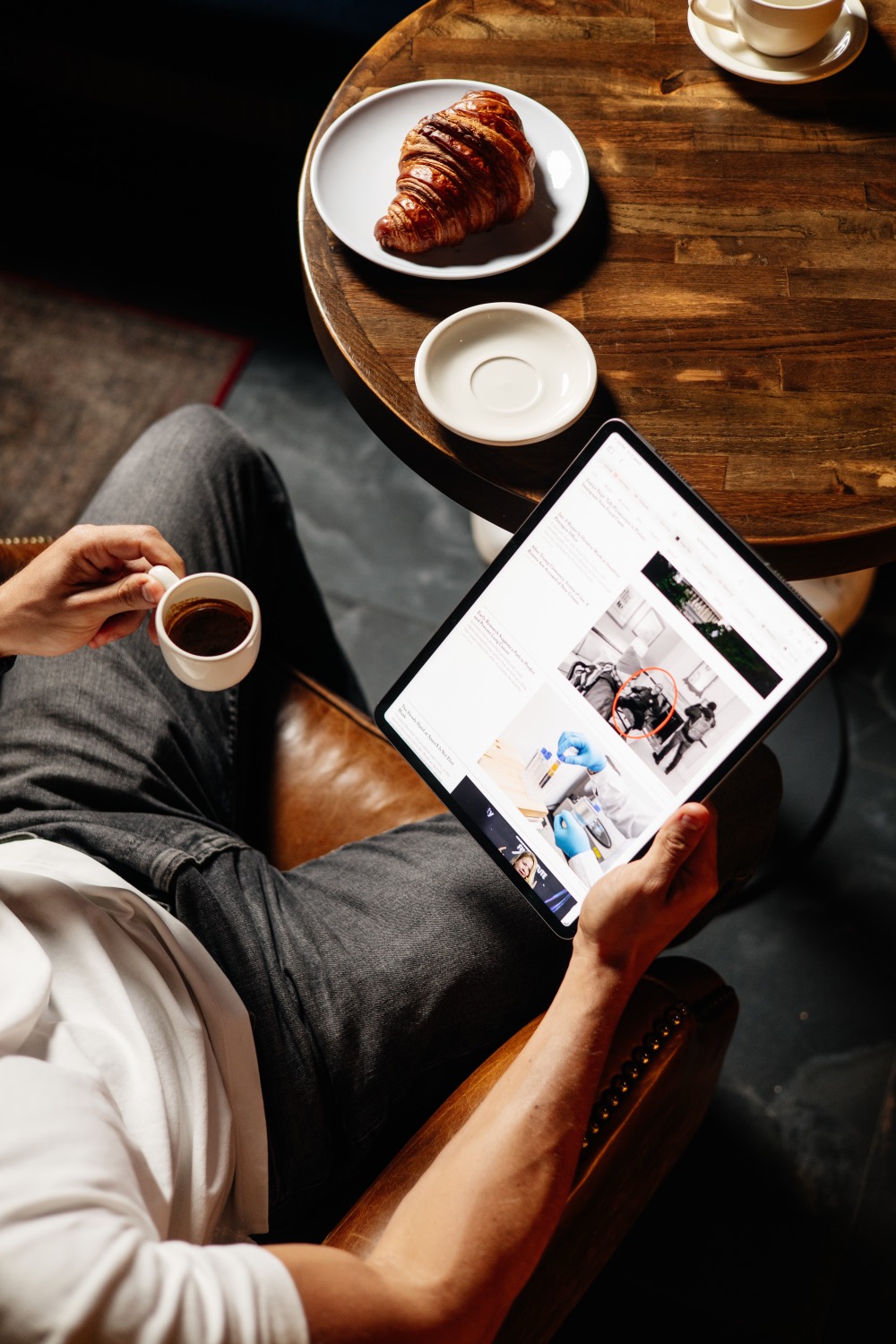 A guest working on a laptop with a coffee and a croissant at It's Him