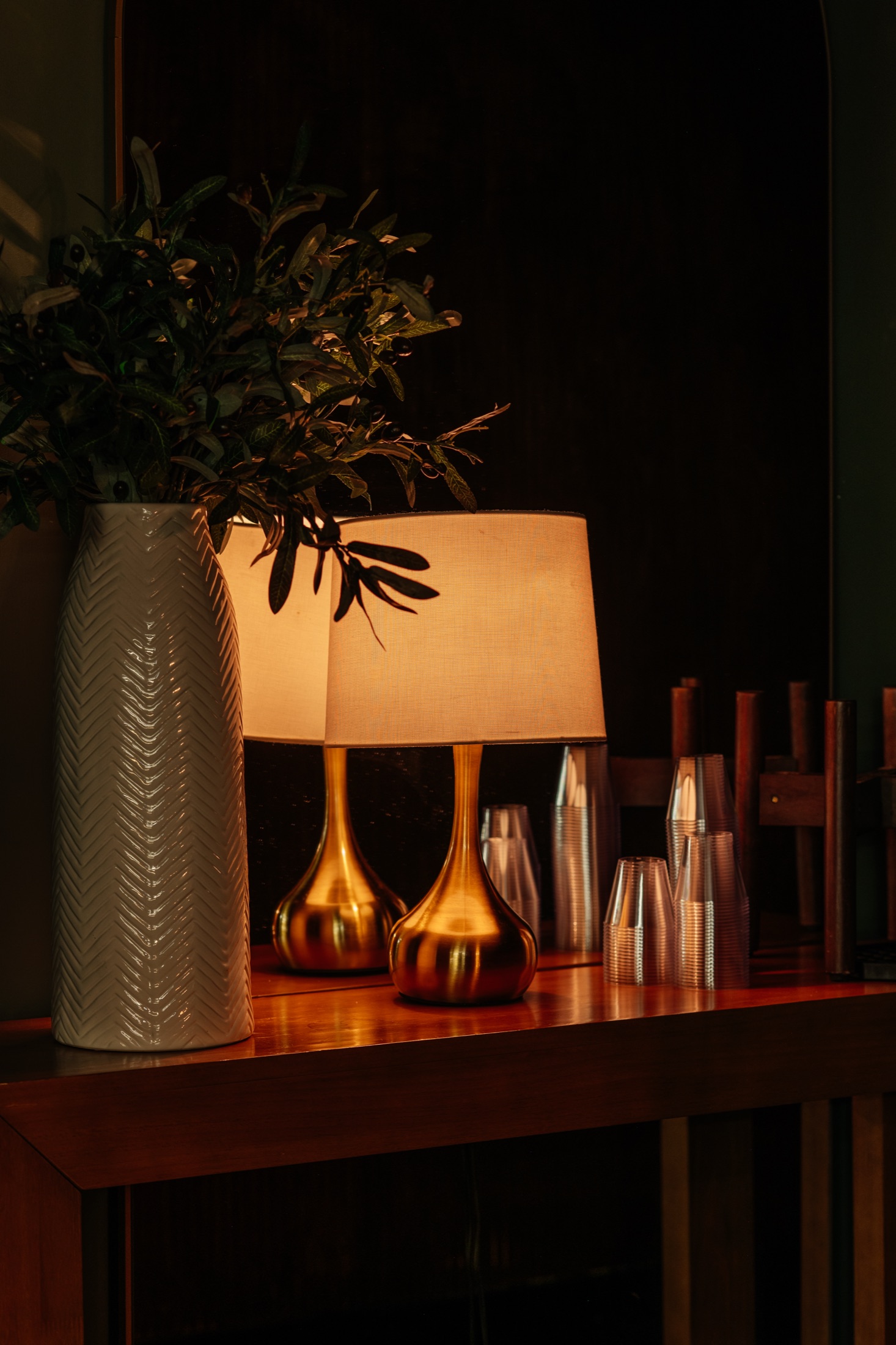 The gold lamp, greenery, and glassware on the bar